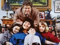 John Goodman in a cast photo for Roseanne, with an Imperial Godzilla figure in the background