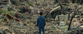 Yaguchi finishes praying in the ruins of an area destroyed by Godzilla