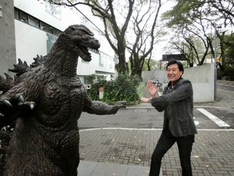 Bin Furuya posing with the Godzilla statue in front of Toho Studios