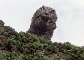 Godzilla peeking over a mountain